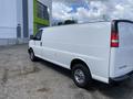 2023 GMC Savana cargo van with a white exterior and chrome wheels parked on a gravel surface