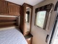 Interior of a 2013 Outdoor Wind River featuring a wooden cabinet with a mirror and a bed with a white quilted mattress