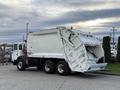 A white 2010 Autocar Xpeditor garbage truck with a rear-loading compactor and large opening for waste disposal