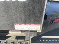 A 2024 Southland 18 Foot Dump Trailer with a metal frame and warning labels attached to the side displaying safety information and instructions