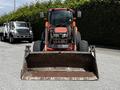 A 2011 Kubota M8540D tractor with a front loader attachment and large tires positioned in a parking area