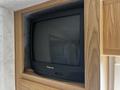 A Panasonic television is mounted in a wooden cabinet inside the 2000 Ford Motorhome