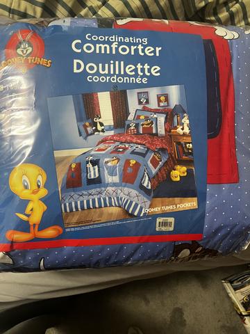 Looney Tunes bed comforter featuring cartoon characters and bright colors with an illustration of Tweety Bird and other designs on a blue background