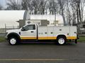 A 2019 Ford F-550 with a white and yellow service body truck designed for utility tasks featuring a ladder rack and side compartments for tools and equipment