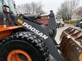 A 2018 Doosan DL300-5 loader with a large bucket at the front and rugged tires, showcasing its branding and heavy-duty design