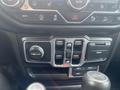 Interior controls and dashboard of a 2020 Jeep Wrangler featuring various knobs switches and buttons for climate and audio settings