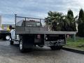 A 2017 GMC Sierra 3500HD with a flatbed and mesh backrest is parked with its rear visible showcasing its sturdy design and dual rear wheels