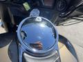 A shiny chrome fuel cap on a 2004 Harley-Davidson Flhtcui motorcycle with a reflective surface and a hand holding a phone in the reflection