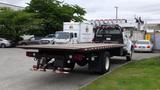 A white 2008 Ford F-750 flatbed truck parked with a wooden flatbed visible and the rear view showing red and white lights