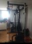 A multi-functional gym rack with various attachments and a stationary bicycle integrated into the design