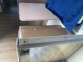A brown upholstered bench seat next to a light wood table with a blue fabric draped over it inside a vehicle