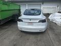 A white 2022 Tesla Model 3 parked with its rear facing the viewer showcasing its sleek design and Tesla emblem