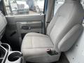 A gray cloth driver's seat of a 2010 Ford Econoline with a console and door handle visible to the left