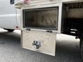 A silver metal tool box with a hinged door is mounted on the side of a truck bed, featuring a latch mechanism for secure closure