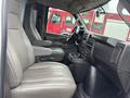 Interior view of a 2022 GMC Savana showing two front seats with armrests and a dashboard with controls and cup holders