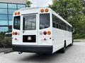 A 2015 Spartan School Bus in white with multiple rear lights and windows visible on the sides and back