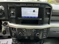 Interior dashboard of a 2024 Ford F-550 featuring a touchscreen display with audio controls and various knobs for climate and media settings