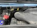 Close-up of the engine compartment of a 2009 Ford Econoline showing the air intake and battery with visible dirt and wear on components