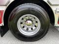 Close-up of a shiny chrome wheel and tire of a 2002 Sutphen Monarch fire truck featuring deep treads and the manufacturer's logo on the tire sidewall