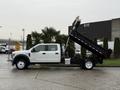 A white 2022 Ford F-550 dump truck with the bed tilted upwards ready for unloading