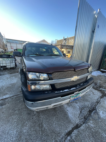 A dark brown 2004 Chevrolet Silverado 1500 truck is parked with a frost-covered hood and chrome grille visible in the foreground