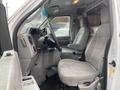 Interior of a 2011 Ford Econoline showing two cloth seats and a steering wheel with controls in the foreground