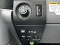 Dashboard controls of a 2013 Ford F-650 featuring a dial for lights a button and three switches labeled PTO UP and DOWN