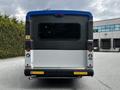 A 2019 Chevrolet Express van with a blue top and gray lower body featuring rear windows and bumper stickers that read Thank you for your Braille Please yield its late