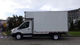 A 2018 Ford Transit cargo van with a white box body and black trim parked on a driveway