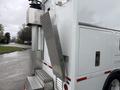 A 2011 Ford F-650 with a white exterior featuring a silver diamond plate step and access panel on the rear side