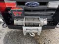 A 2007 Ford F-550 with a mounted winch on the front bumper featuring a steel cable and fairlead
