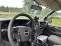 Interior view of a 2014 GMC Savana showing the steering wheel dashboard and front console with a phone holder and documents on the center console