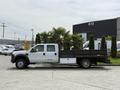 A 2008 Ford F-550 truck with a flatbed and a white cab parked on a lot showcasing its side profile and a black rear section