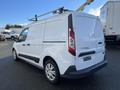 White 2017 Ford Transit Connect van with a roof rack and sliding side door viewed from the rear angle