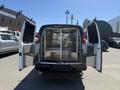 A 2007 Chevrolet Express van with its rear doors open revealing a spacious interior with metal shelving and a clean storage area