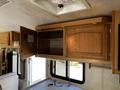 Interior of a 2000 Ford Motorhome featuring wooden cabinets with a partially open door and a kitchen sink visible below