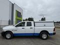 White 2016 RAM 1500 pickup truck with a blue stripe and a covered bed in a side view