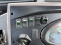 Close-up of the control panel of a 2005 Case 570 with multiple switches and a gauge displaying engine temperature and fuel levels
