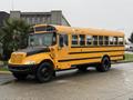 A yellow 2013 International 3000 school bus with black accents parked with its doors closed and a clear view of its windows and wheels