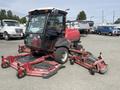 A 2012 Toro Groundsmaster 5910 with a cab and three mowing decks attached at the front and sides in a parking area