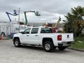 A white 2016 GMC Sierra 1500 pickup truck is parked, showcasing its sleek design and chrome details with a standard truck bed and side steps