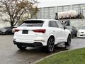 A 2024 Audi Q3 in white with a sleek design and black accents showing the rear view and sporty wheels