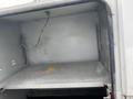 The image shows the interior of a storage compartment in a 2003 Ford F-450 SD featuring a metal shelf and bare metal walls