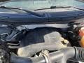 The engine of a 2014 Ford F-150 is visible with parts such as the air intake and various hoses shown prominently