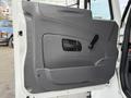 A gray interior door panel of a 2011 International 4300 with a handle and a small window opening