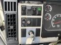 Dashboard of a 2003 Freightliner FL70 with various controls including wiper, cruise, and light switches along with a key ignition and gauges for speed and RPM