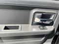 The interior door panel of a 2011 RAM 1500 featuring a chrome door handle a window control button and a storage pocket