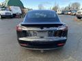 A black 2019 Tesla Model 3 viewed from the rear showcasing its sleek design and modern features without any visible license plate or markings