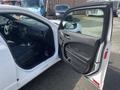 A white 2017 Dodge Charger with the driver's side door open, showcasing the interior features and dashboard