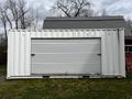 A 40 foot storage container with a roll-up door positioned on a grassy area